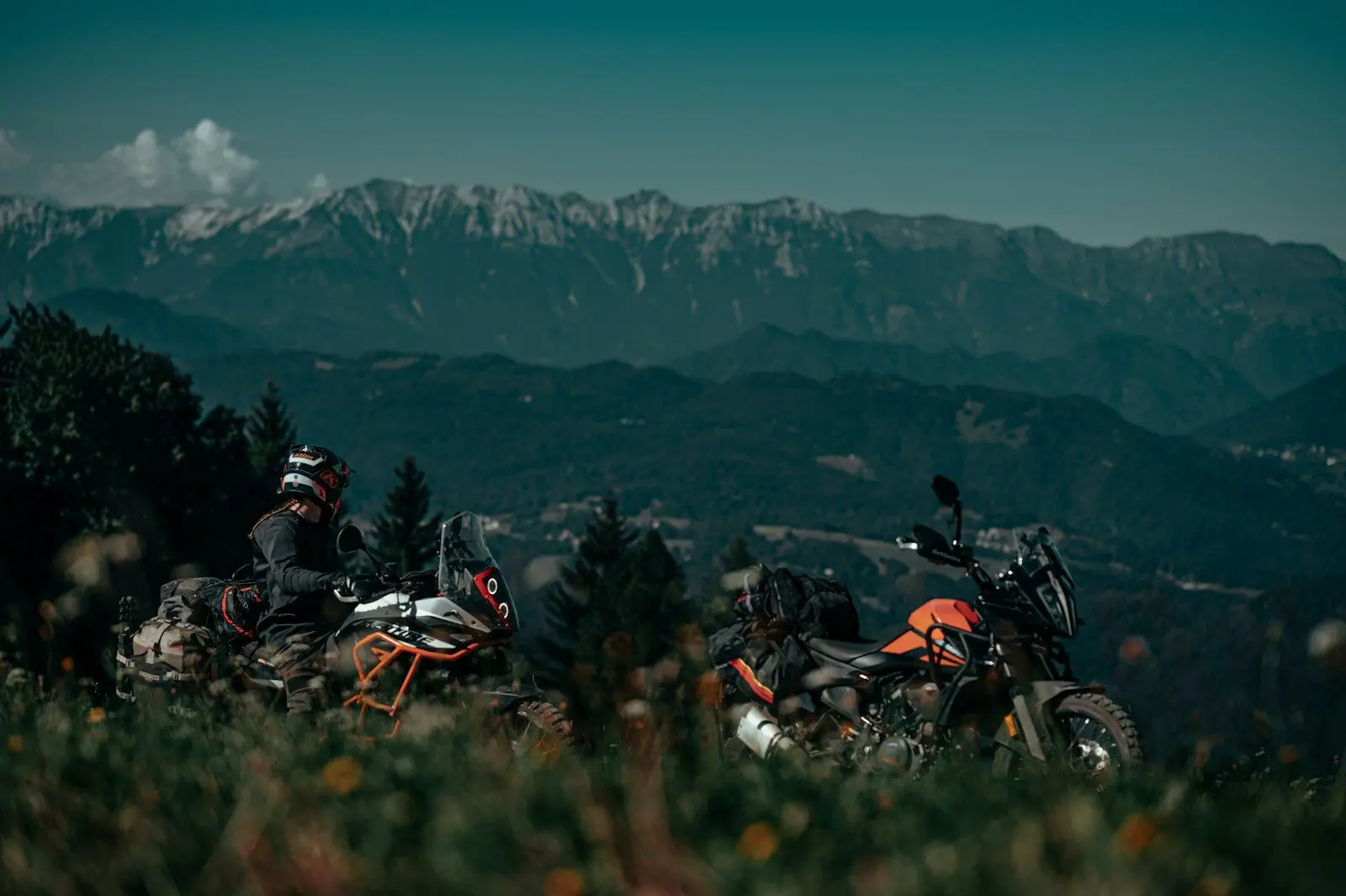 A couple of motorcycles parked on top of a lush green hillside