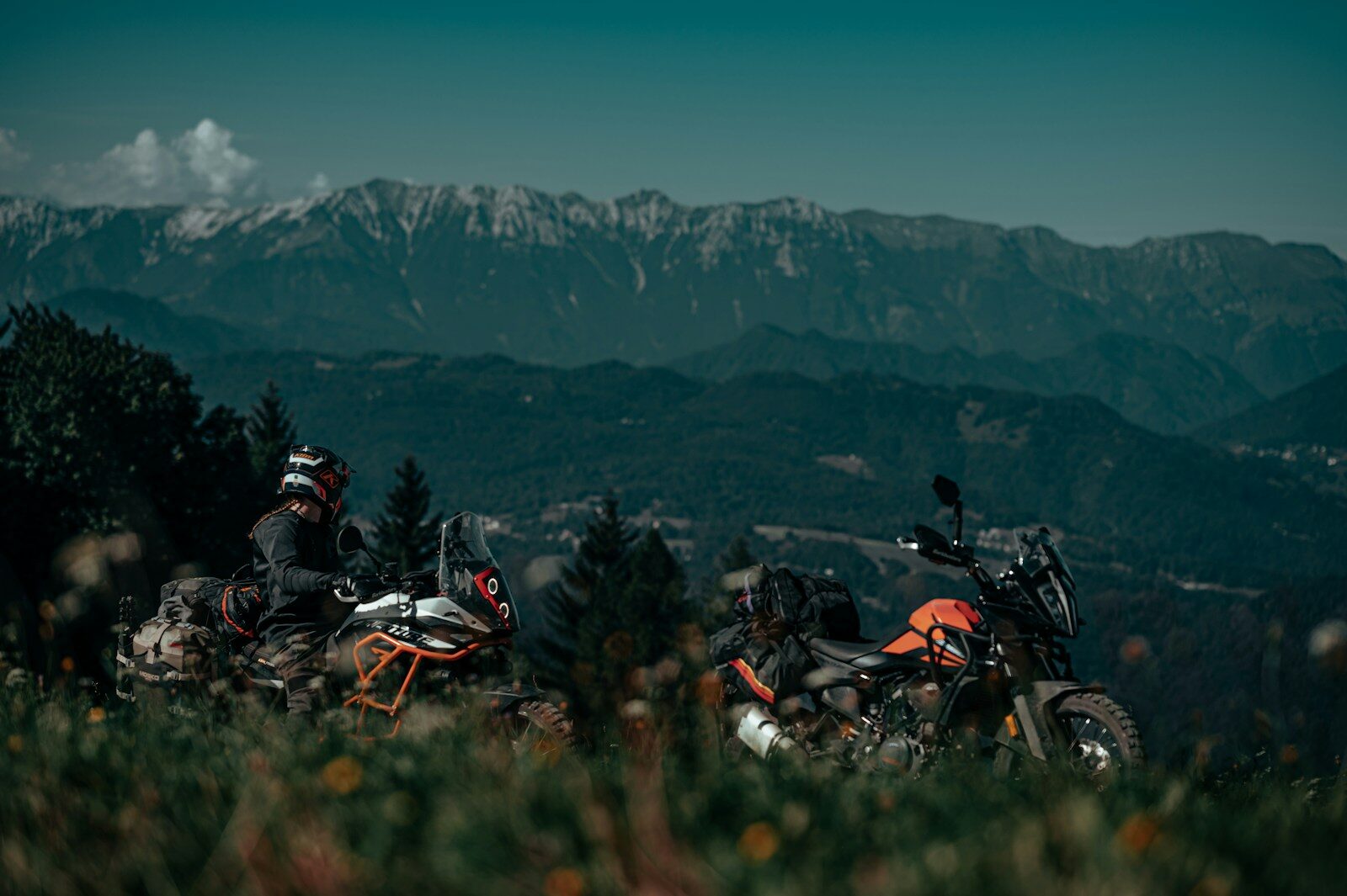 A couple of motorcycles parked on top of a lush green hillside